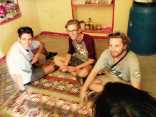 three men sitting on a bed in a room at Madhu Singh Dhani Home Stay -Ridmalsar in Champasar