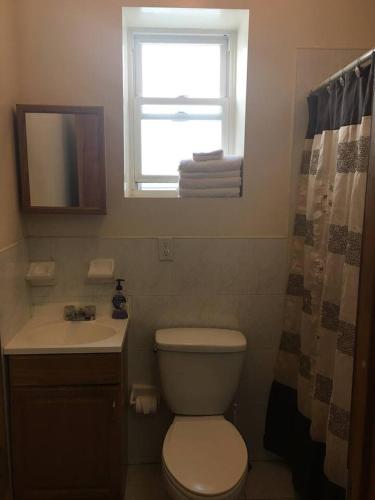 een badkamer met een toilet, een wastafel en een raam bij A private humble abode in Brooklyn