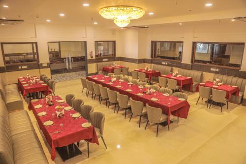ein Restaurant mit roten Tischen und Stühlen sowie einem Kronleuchter in der Unterkunft Dhauladhar Heights Resort in Dharamshala