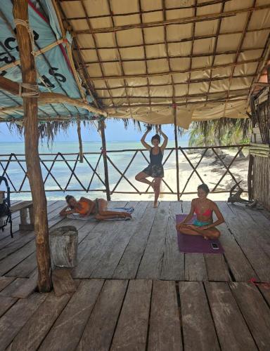 three people sitting on the floor under a pavilion on the beach at sanblasonsailboats in El Porvenir
