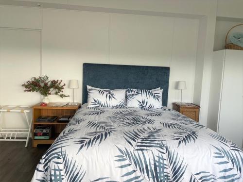 1 dormitorio con 1 cama grande y cabecero azul en Pickmere Waters, en Kerikeri