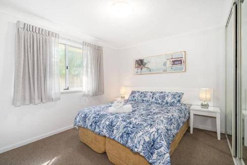 Schlafzimmer mit einem Bett mit einer blauen und weißen Bettdecke in der Unterkunft Ocean Blue Bungalow - Unit 24 at Cape View Resort in Broadwater