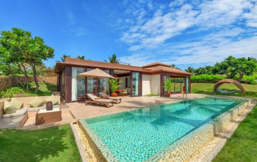 a swimming pool in front of a villa at Fusion Resort Cam Ranh - All Spa Inclusive in Cam Ranh