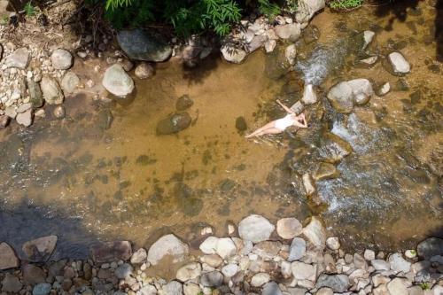 a person swimming in a stream of water with rocks at เดอะริเวอร์ แม่กำปอง The River Maekampong Chiang Mai in Ban Pok Nai