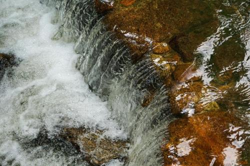 a close up of a stream of water on rocks at เดอะริเวอร์ แม่กำปอง The River Maekampong Chiang Mai in Ban Pok Nai