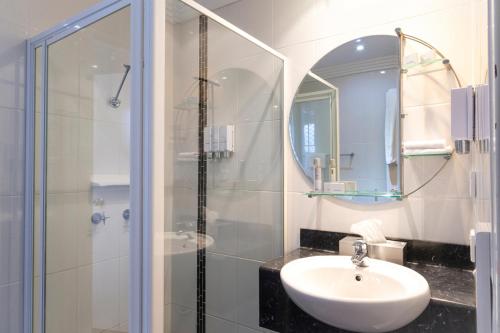 uma casa de banho com um lavatório e um chuveiro com um espelho. em Parkes International em Parkes