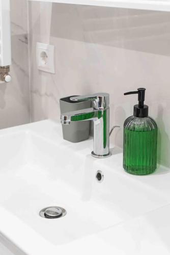 a bathroom sink with a green soap dispenser on it at RentWill apartments Double in Chişinău