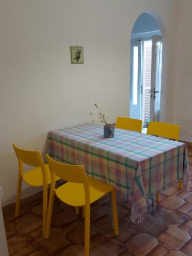 a dining room table with yellow chairs and a blue and yellow table cloth at Casa nel centro storico a Loreto, 2 km dal mare in Loreto