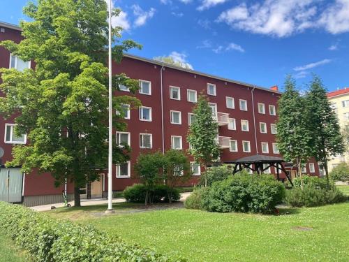 ein großes rotes Gebäude mit einem Rasenplatz davor in der Unterkunft Kaski, three-room condo in a prime location, free parking in Tampere