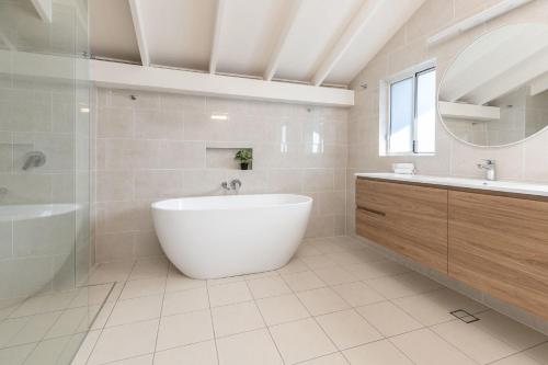 a white bathroom with a tub and a sink at The Pole House in Elizabeth Beach