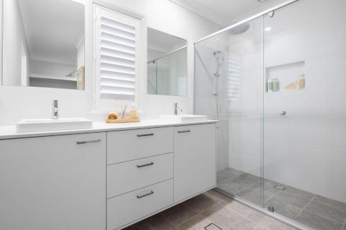 - une salle de bains blanche avec deux lavabos et une douche dans l'établissement Spoondrift - Pet Friendly - 5 Mins Walk to Beach, à South West Rocks