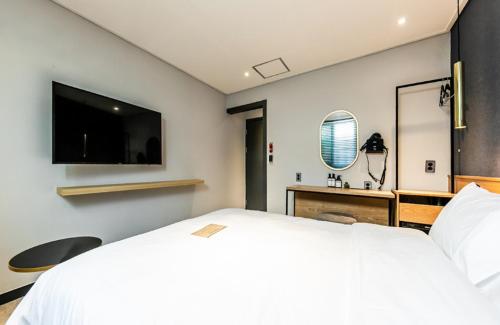 a bedroom with a large white bed and a desk at Hotel No. 25 Gyeongju bus terminal in Gyeongju