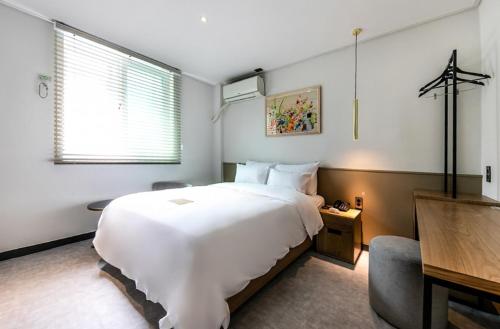 una camera con un grande letto bianco e una scrivania di Hotel No. 25 Gyeongju bus terminal a Gyeongju