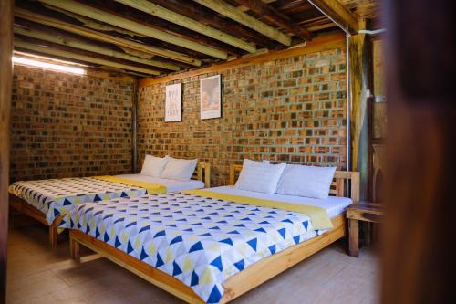 two beds in a room with a brick wall at SEN VILLA Boutique in Bao Loc