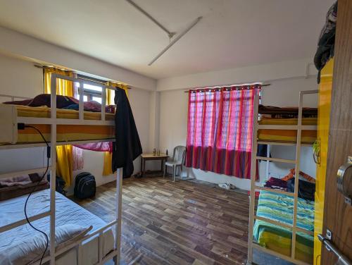 a room with three bunk beds and a desk at Mochilero Ostello in Pelling