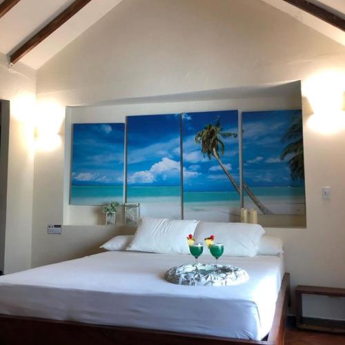 a bedroom with a bed with two drinks on a tray at Hotel Tropical in isla de punta arena in Cartagena de Indias