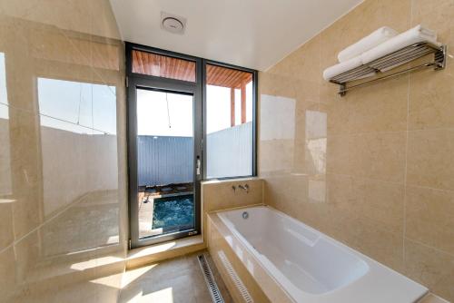 a bathroom with a bath tub and a window at Jeju Breeze in Seogwipo