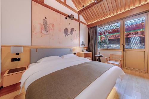 um quarto com uma cama grande e uma janela grande em Xinxiang Yayuan Beijing Sihe courtyard with sky garden terrace Near Tiananmen Square Forbidden City Wangfujing Pedestrian Street and the subway em Pequim