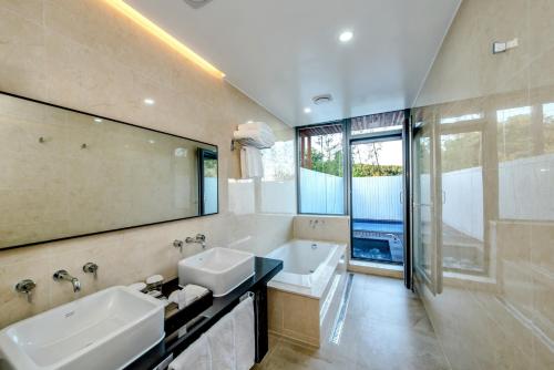 uma casa de banho com 2 lavatórios, uma banheira e um espelho. em Jeju Breeze em Seogwipo