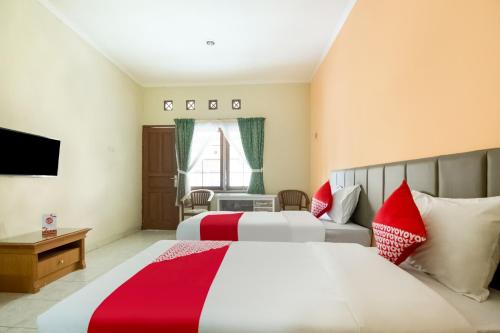 Cette chambre comprend deux lits et une télévision. dans l'établissement SUPER OYO 3335 Wisma Langen Werdhasih, à Semarang