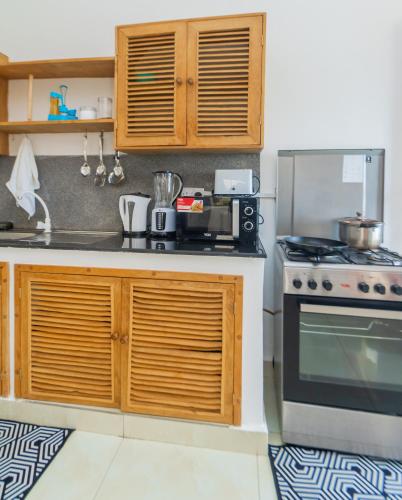 a kitchen with a stove and a microwave at Chameleon house diani in Ukunda