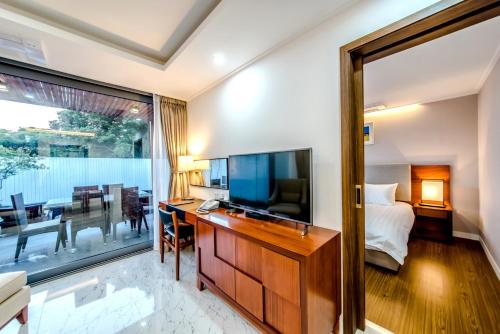 a hotel room with a television and a bedroom at Jeju Breeze in Seogwipo