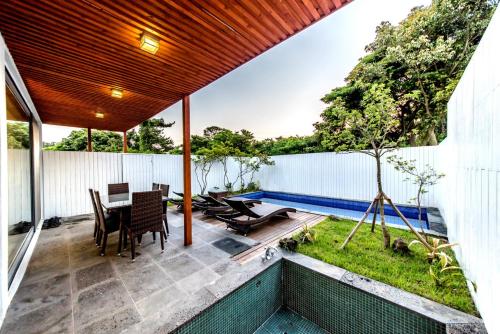a patio with a table and chairs and a swimming pool at Jeju Breeze in Seogwipo