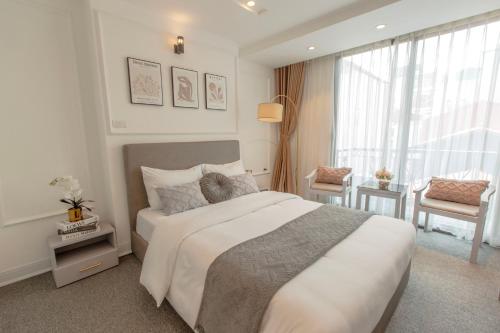a white bedroom with a large bed and a window at Keypad Hotel - 87 Nguyễn Khang in Hanoi