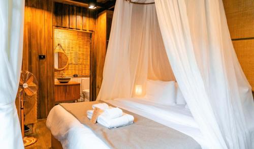 a bedroom with a bed with white sheets and towels at อุ่นไอมาง สะปัน in Ban Huai Ti