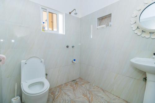 een witte badkamer met een toilet en een wastafel bij Chameleon house diani in Ukunda