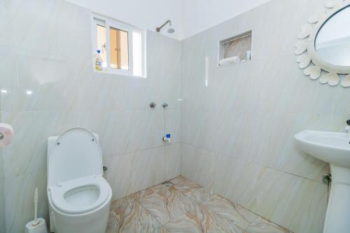 a white bathroom with a toilet and a sink at Chameleon house diani in Ukunda