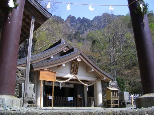 a small shrine with a mountain in the background at Fukeikan 風景館 in Takayama