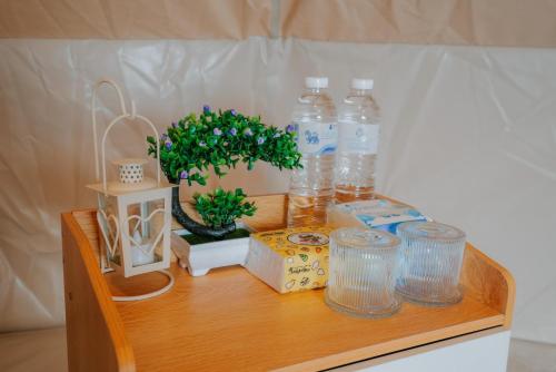 a wooden table with bottles of water and a plant at ฮิมสวน โฮมสเตย์ Him suan homestey in Ban Thung Phan Ha