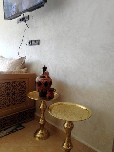 una mesa con un jarrón junto a una cama en Meknès kamilia, en Meknès