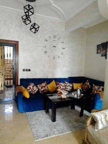 niebieską kanapę w salonie z zegarem na ścianie w obiekcie Meknès kamilia w mieście Meknès