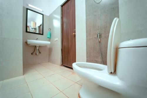 a bathroom with a toilet and a sink and a mirror at Atulyam Villa- Anjuna in Anjuna