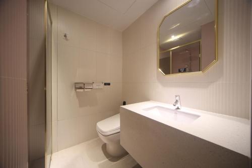 a bathroom with a sink and a toilet and a mirror at H Avenue Hotel Minam in Busan