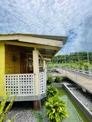 a small yellow building with a porch and water at Jazz Ferme Inn Batuan Bohol in Batuan