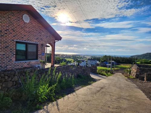 a brick house on a hill with a dirt road at Sunshine Aewol Entire House in Jeju