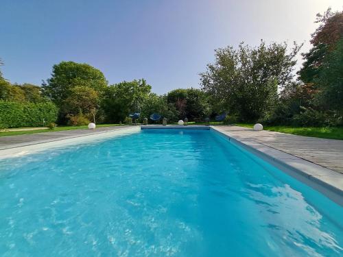 a swimming pool with blue water in a yard at Léalie in Gonneville-sur-Honfleur