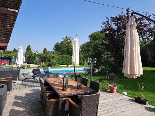 un patio con una mesa con sombrillas y una piscina en Léalie, en Gonneville-sur-Honfleur