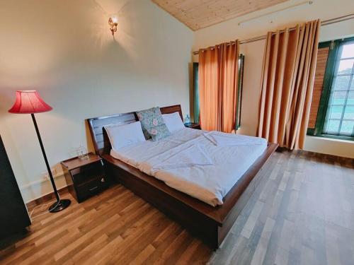 a bedroom with a bed and a lamp in a room at Aviator's Bungalow - Dharamshala in Dharamshala