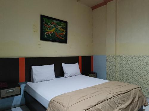 - une chambre dotée d'un lit blanc avec une photo sur le mur dans l'établissement OYO 93046 Hotel Fortuna Parepare, à Parepare