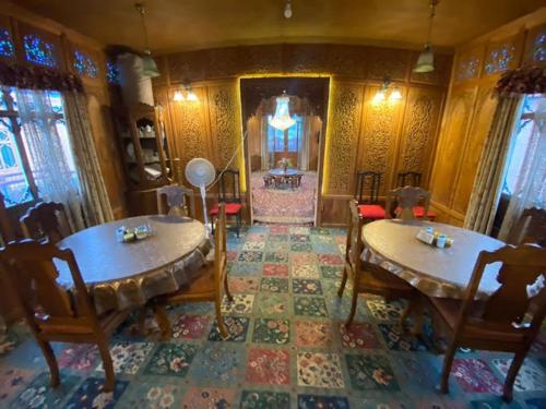 ein Wohnzimmer mit 2 Tischen und Stühlen und ein Zimmer mit einem Kamin in der Unterkunft Houseboat Kashmir Treat in Srinagar