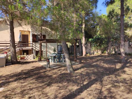 a yard with a table and trees in front of a house at Casa Sonia in Porto Pino
