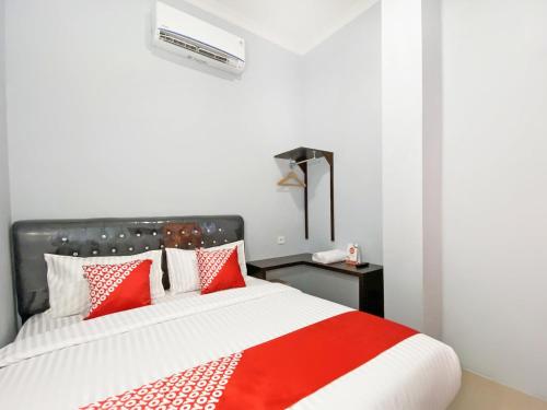 a bedroom with a bed with red and white pillows at OYO 3160 Guesthouse Pagi Sore Syariah in Padang