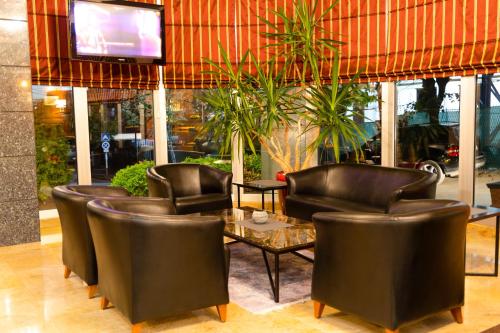 a restaurant with leather chairs and a table and a tv at Hotel Ambasador Prishtina in Prishtinë