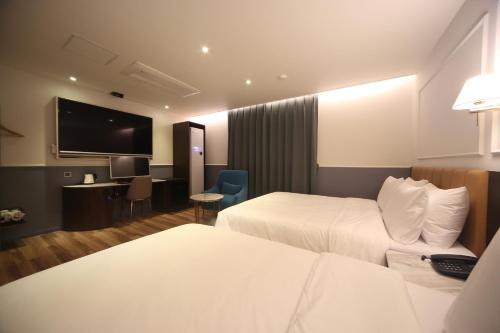 a hotel room with two beds and a flat screen tv at H Avenue Hotel Minam in Busan