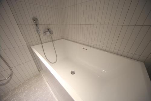 a white bath tub with a shower in a bathroom at H Avenue Hotel Minam in Busan