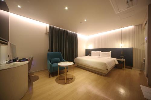Habitación de hotel con cama y silla azul en H Avenue Hotel Minam en Busan